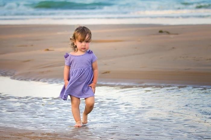 Маленькая девочка идет по пляжу