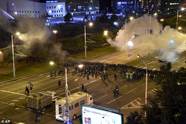 A line of police block a road while tear gas wafts in the background during mass protests in Minsk which saw thousands of people turn out to demonstrate on Tuesday