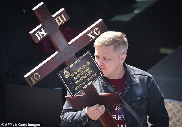 A man carries a cross during the funeral ceremony of Alexander Taraikovsky, a 34-year-old protester who died on August 10, in central Minsk today
