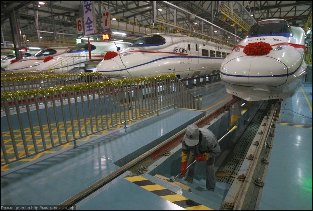 A labourer cleans the stairs beside a China Railway High-speed train preparing for the operation ceremony from Wuhan to Guangzhou in Wuhan