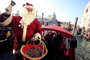 A man dressed as Santa Claus distributes candy in front of a special Christmas gondola in the canal city of Venice December 18, 2009. REUTERS/Manuel Silvestri (ITALY - Tags: SOCIETY)